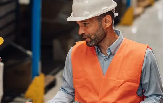 Warehouse supervisor talking to team all wearing hard hats