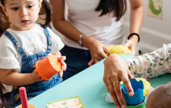 Preschool teacher sitting around table with children