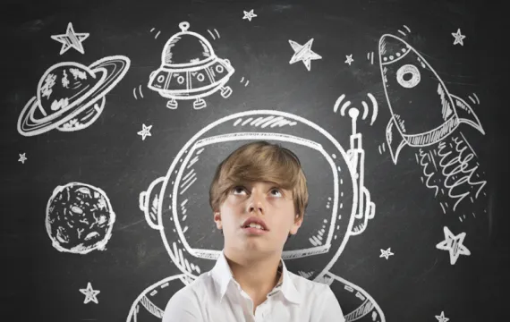 Child in front of a chalkboard with space drawings