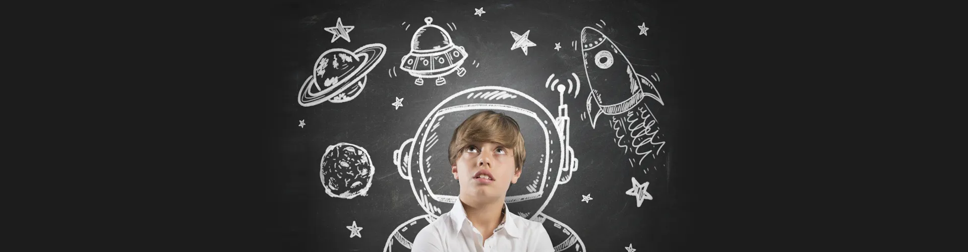 Child in front of a chalkboard with space drawings