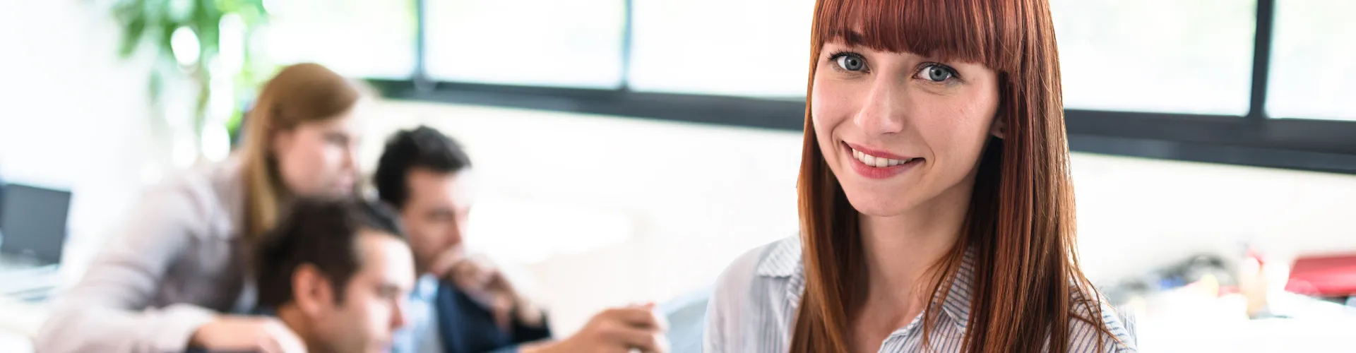 Young employee smiling with colleagues working behind